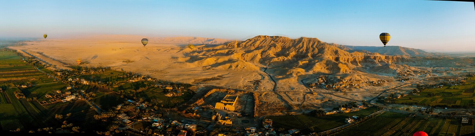 a wonderful view of a hot air balloon flying over the sky of the beautiful city of luxor in egypt