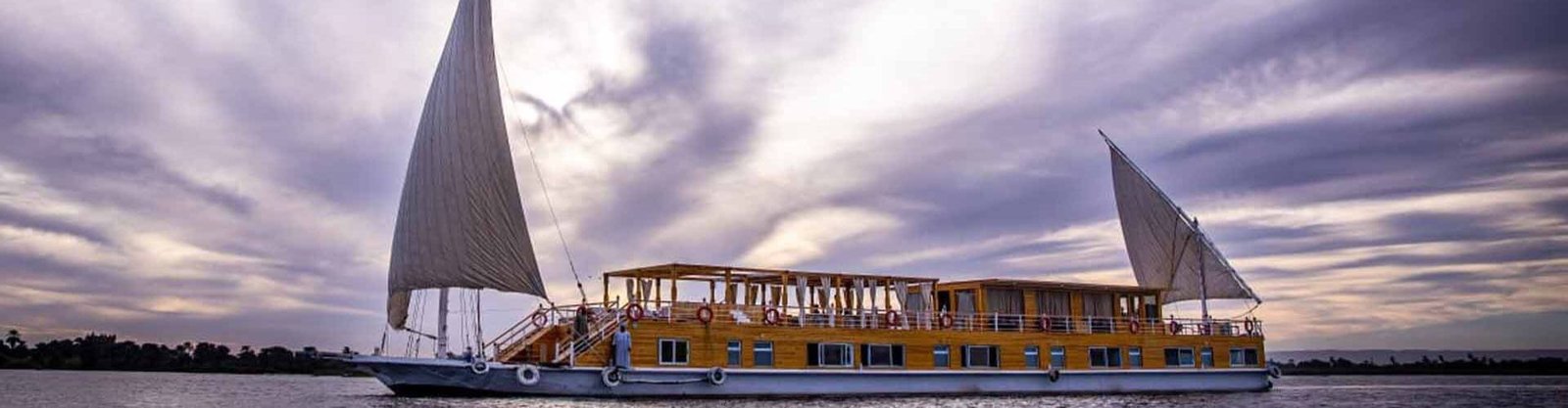 Egypt Nile Cruise aboard the classic Akhnaton Dahabiya sailboat at sunset.