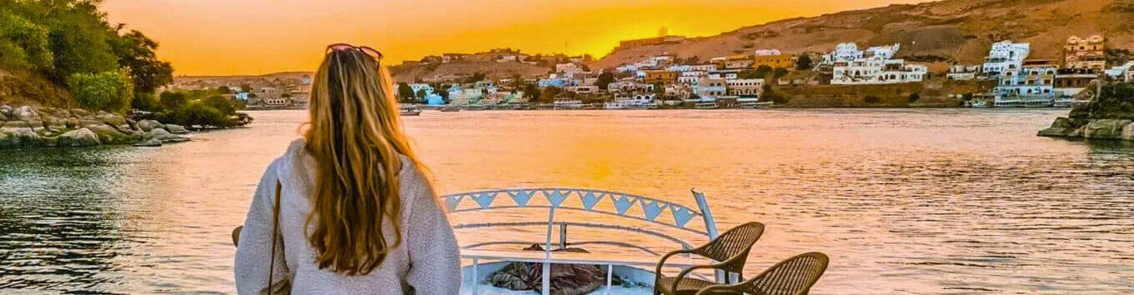 woman watches Nubian Village at sunset on a Nile cruise; helps decide what to pack for a Nile cruise
