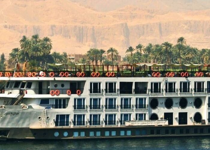 A traditional felucca and a modern ship on the river, a highlight of a Nile Cruise Itinerary.