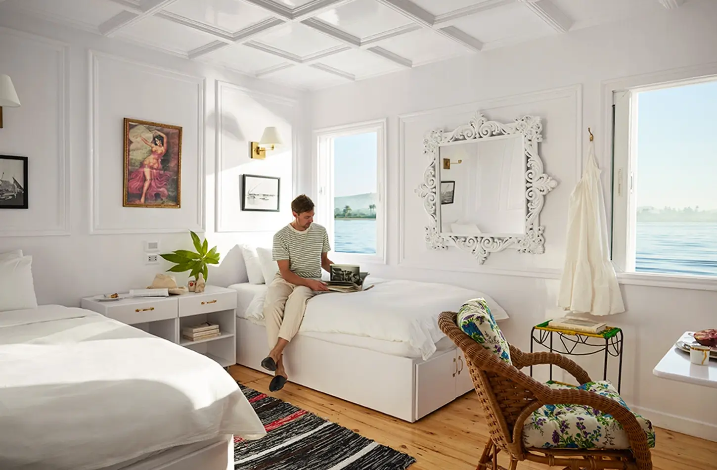 "Man relaxing in a luxury Dahabiya cruise cabin with a scenic view of the Nile River."