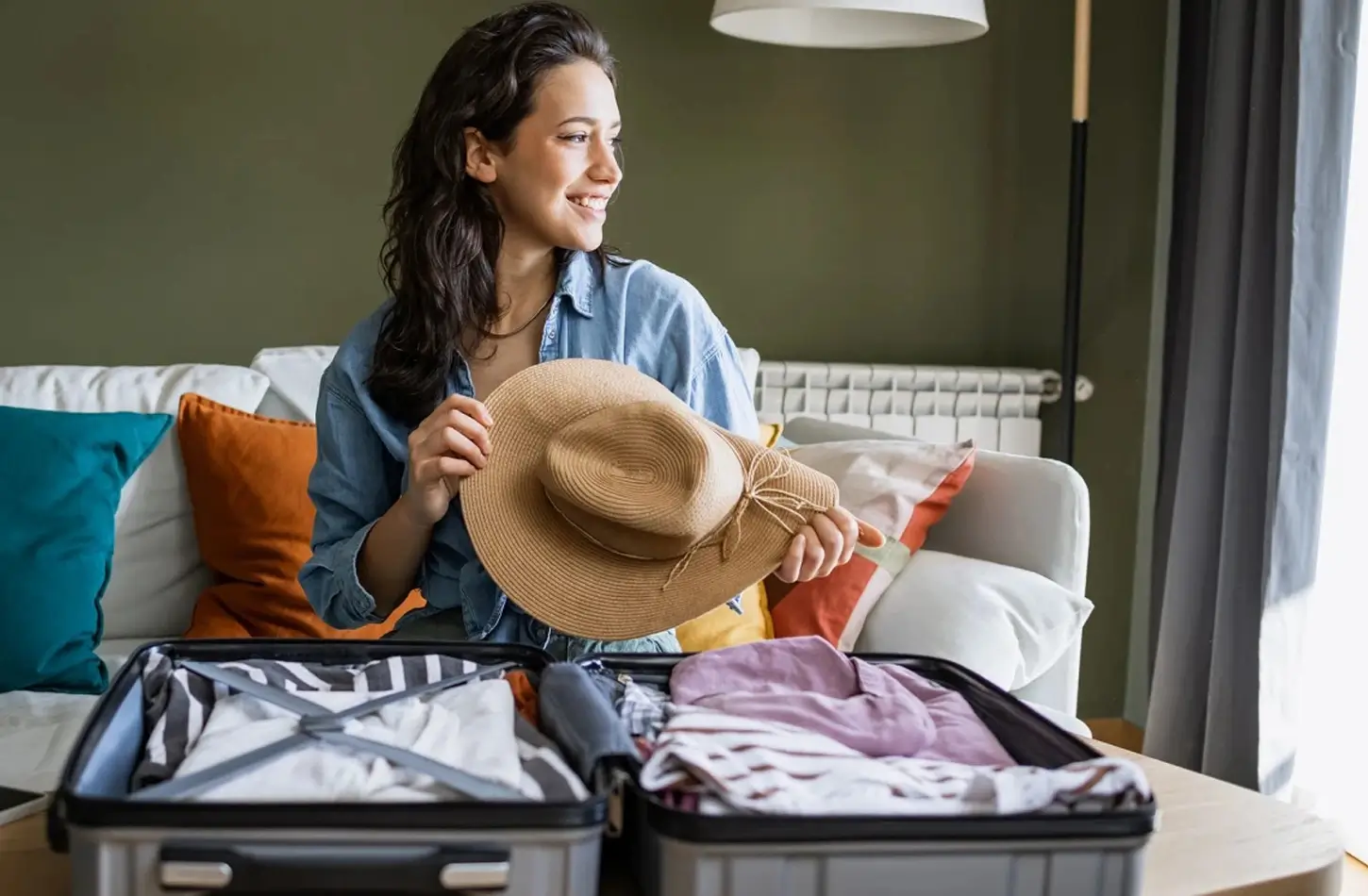 Woman packing essential items like a sun hat and light clothing in a suitcase for an Egypt trip