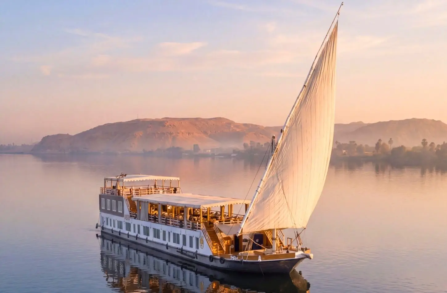 A luxury Dahabiya boat sailing along the Nile River in Egypt under warm sunlight, illustrating is it safe to go on a Nile cruise.