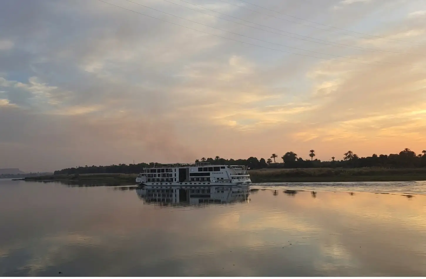 How to Plan a Nile Cruise in Egypt: The Complete Step-by-Step Guide (2026) 2 Cruising vessel sailing along the river at sunset featured in a guide on how to plan a Nile cruise
