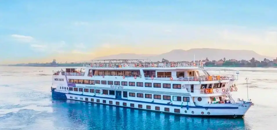 Nile Cruise Cost 2026: Prices by Ship Type & Route 3 The Star of Luxor luxury cruise ship sailing along the calm waters of the Nile River against a scenic backdrop of hills and sky, representing factors that influence the Nile Cruise Cost.